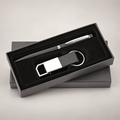 Black pen and rectangular keychain gift set in its presentation box on a warm grey studio background